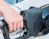 Dłoń trzyma pistolet paliwowy, rozpoczynając tankowanie samochodu.