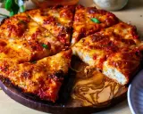 Pyszna pizza rzymska z chrupiącym ciastem, ciągnącym serem i aromatycznym sosem pomidorowym, podana na drewnianej desce.