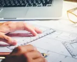 Rysowanie planów, laptop i okulary na biurku. Zastanawiasz się, ile zarabia architekt?