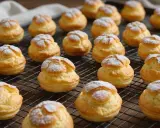 Une grille remplie de choux pâtissiers dorés, saupoudrés de sucre glace. Ils attendent d'être dégustés.
