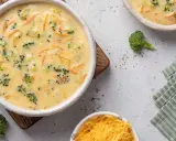 Un cremoso puré de brócoli y zanahoria, con trozos visibles de brócoli y ralladura de queso, servido en un cuenco blanco.