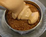 Une crème onctueuse est versée sur une base de croustillant praliné feuilletine dans un cercle à pâtisserie.