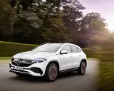 Un Mercedes EQA blanco circula por una carretera rodeada de árboles. Las **mercedes eqa medidas** son ideales para la ciudad y escapadas.