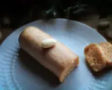 Un bâtonnet de pâte d'amande, garni d'une amande entière, repose sur une assiette blanche. À côté, deux tranches de ce délice, parfait pour un fond de tarte amande.