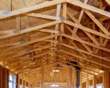 Structure complexe de charpente en bois, avec des fermes et des poutres formant un contreventement bois solide pour une nouvelle construction.