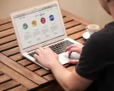 Mężczyzna pracuje na laptopie, przeglądając stronę internetową firmy CyberRabbit. Strona prezentuje usługi: rozwój stron, wsparcie techniczne, grafika i social media. To jest przykład, print co to jest.