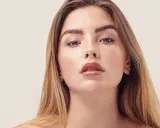 Nahaufnahme einer jungen Frau mit Sommersprossen und dunkelblond hellbraunen Haaren, die glänzend und glatt fallen.