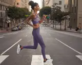 Donna in outfit viola, perfetto per come vestirsi in palestra, corre in strada.