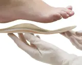 Une orthoplastie sur mesure est présentée sous un pied, tenue par des mains gantées.