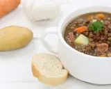 Herzhafte Linsensuppe nach DDR-Rezept mit Kartoffeln, Karotten und Speck. Dazu ein Stück Brot.