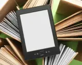 Un e-reader con schermo bianco è circondato da libri aperti, pronti per essere letti.