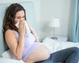Donna incinta con raffreddore, cerca sollievo con un fazzoletto. La scelta di un antistaminico in gravidanza richiede attenzione.