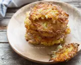 Una pila di dorate frittelle di patate su un piatto di legno. Croccanti fuori, morbide dentro, perfette per uno spuntino.