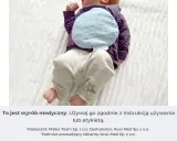 Niemowlę z termoforem z pestek wiśni na brzuszku. Dowiedz się, jak zagrzać taki termofor, by przyniósł ulgę.