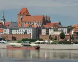 Widok na średniowieczny zespół miejski Torunia z Wisły. W oddali katedra i kamienice, na pierwszym planie barka.