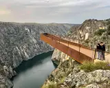 Pareja admira el paisaje desde el mirador del fraile, una pasarela metálica que se adentra en un cañón con un río.