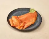 Räucherlachs auf dunkler Platte, garniert mit einer Limettenscheibe. Perfekt für einen Caipirinha-Lachs-Genuss.