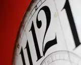 Zbliżenie na cyferblat zegara z dużymi, czarnymi cyframi 11 i 12. Nieważne, czy jest to am to rano czy wieczorem, czas płynie.