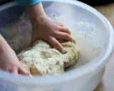 Mains d'enfant pétrissant une pâte à pizza dans un bol. Une étape clé de la recette pâte à pizza levure sèche.