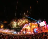 Feuerwerk über einer riesigen Menschenmenge bei Konzerten in Lissabon. Die Bühne ist mit Lichtern und Bildschirmen geschmückt, während die Menge jubelt.