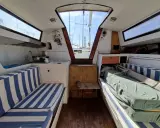 Intérieur d'un voilier avec banquettes bleues et blanches. Une fiche technique du voilier Sangria pourrait inclure ces détails.