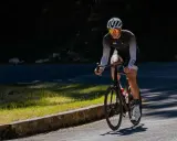 Kolarz na rowerze, pracują mięśnie nóg i pośladków.