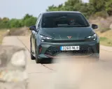 La Cupra Born VZ, d'un vert profond, roule sur une route de campagne. Un conducteur porte des lunettes de soleil.