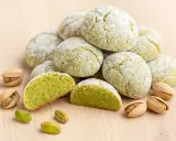 Amaretti pistache saupoudrés de sucre glace, avec des pistaches entières et décortiquées. Une recette gourmande à découvrir.