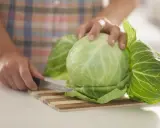 Ręce kroją kapustę na desce. Liście kapusty są gotowe na okłady z kapusty.