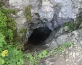 Wejście do Smoczej Jamy w Tatrach, otoczone zielenią i skałami. Ciemny otwór zaprasza do tajemniczego wnętrza.