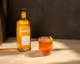 Butelka Bushmills 15 Year Old Single Malt Irish Whiskey obok szklanki z drinkiem. Wiele pozytywnych bushmills whisky opinie potwierdza jego wyjątkowy smak.