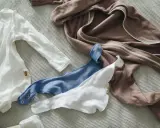 Brązowy pajacyk z zamkiem i zatrzaski przy bluzie, biały i niebieski śliniaczek.