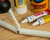 Klej w pistolecie aplikowany na pękniętą białą rurkę. Obok tubki z klejem "Clear" i puszka "Contact Adhesive" - idealne, by dowiedzieć się, czym skleić plastik.