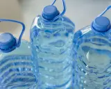 Trzy duże, niebieskie butelki z wodą, każda z uchwytem. Zastanawiasz się, ile może stać woda w plastikowej butelce po otwarciu?
