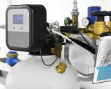 Système de traitement d'eau moderne, avec écran digital affichant "5354". Ce dispositif, conçu par un fabricant adoucisseur d'eau, est entouré de tuyauterie en laiton et de vannes.
