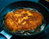 Złocisty kotlet schabowy smaży się na patelni. Idealnie chrupiąca panierka i bulgoczący tłuszcz świadczą o tym, jak długo smażyć schabowe, by były perfekcyjne.