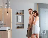 Glückliches Paar im Bad, neben dem besten Durchlauferhitzer. Modernes Bad mit Dusche und Waschbecken.