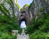 Eine lange Treppe führt durch eine Schlucht mit üppiger Vegetation hinauf zu einem riesigen Felsentor, den "Stairs to Heaven" in China.