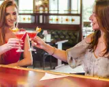 Dwie przyjaciółki wznoszą toast drinkami w barze. Idealny weekend z przyjaciółką!