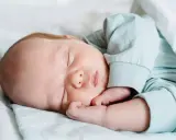Un tierno recién nacido duerme plácidamente envuelto en mantas. Su carita serena y sus manitas descansan, disfrutando de un profundo sueño.