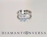 Un anello prezioso con tre diamanti scintillanti, riflesso su una superficie lucida.