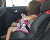 Niña en silla de coche, lista para el viaje. Aún no es el momento cuando puede ir un niño sin silla en el coche.
