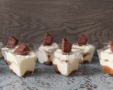 Słodkie deserki w pucharkach, przypominające tort Kinder Bueno, z kremem i kawałkami czekolady.