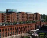 Dawna fabryka w Łodzi, dziś centrum handlowe i rozrywkowe. Widać tu architekturę z czerwonej cegły, parking, ogródki kawiarniane i karuzelę, tworząc ciekawe łódzkie atrakcje.
