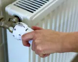Dłoń reguluje termostat grzejnika. Kiedy zaczyna się sezon grzewczy? Zazwyczaj od października do kwietnia.