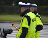 Policjant w kamizelce odblaskowej trzyma alkomat. Czy policja może badać alkomatem w domu? To pytanie często zadawane przez kierowców.