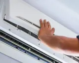 Mano ajustando el aire acondicionado para que renueve el aire.