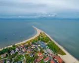 Malownicza miejscowość nad morzem z domkami i plażą, otoczona wodą.