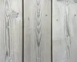 Grå träpanel med tydlig ådring, som efter kiselbehandling altan. Perfekt för en modern och hållbar uteplats.