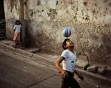 Un bambino gioca con una palla a strisce, catturato dall'obiettivo di David Alan Harvey. Una bambina osserva sullo sfondo.